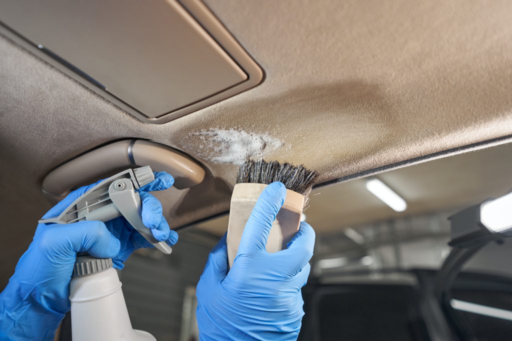 Car wash worker cleaning car interior with brush